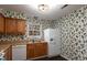 Kitchen with wood cabinets, white appliances, and floral wallpaper at 6409 New Market Way, Raleigh, NC 27615