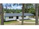 White ranch home with a dark gray roof, nestled among trees at 889 Burlington Rd, Roxboro, NC 27573