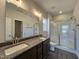 Bathroom featuring double sinks, granite countertops, framed mirror, and a glass-enclosed shower with tile surround at 286 Longbow Dr, Middlesex, NC 27557
