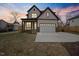 Charming two-story home featuring light siding, dark trim, covered porch, and an attached two-car garage at 112 1St St, Oxford, NC 27565