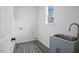 Bright laundry room boasts a utility sink and gray wood floors at 112 1St St, Oxford, NC 27565