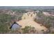 Aerial view of a house with a pond, pastureland, and lush surrounding forest at 1200 Spring Valley Lake Rd, Henderson, NC 27536