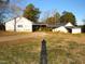 Exterior view of the home featuring a covered parking area, a spacious yard and mature trees at 1200 Spring Valley Lake Rd, Henderson, NC 27536