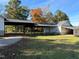 View of the home's exterior, showcasing a covered parking area and well-maintained lawn with mature trees at 1200 Spring Valley Lake Rd, Henderson, NC 27536