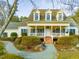 Two-story yellow house with wrap-around porch and landscaped yard at 250 Kentview Dr, Pittsboro, NC 27312