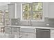 Bright kitchen featuring a white farmhouse sink, stainless steel dishwasher and a window view of wooded landscape at 3400 Amelia Grace Dr # 46, Fuquay Varina, NC 27526