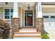Inviting front porch featuring stone columns, a dark wood door, and a hanging light fixture at 4538 Brighton Ridge Dr, Apex, NC 27539