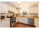 Galley kitchen with white cabinets, stainless steel appliances, and wood floors at 6700 Chauncey Dr, Raleigh, NC 27615