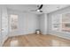 Bright bedroom featuring light wood floors, a ceiling fan, and ample natural light from two large windows at 105 Fountain Ridge Pl, Holly Springs, NC 27540