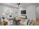 Bright living room featuring light wood floors, a ceiling fan, and ample natural light from large windows at 105 Fountain Ridge Pl, Holly Springs, NC 27540