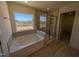 A well-lit bathroom featuring a soaking tub, separate glass shower, and large window at 143 Steppe Way, Garner, NC 27529