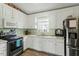 Kitchen with white cabinets, black appliances, and a double sink at 154 Kirkwall Ln, Selma, NC 27576