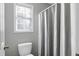 Cozy bathroom features a toilet, shower with curtain, and a window for natural light and ventilation at 109 Stoneline Ct, Holly Springs, NC 27540