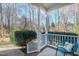 Front porch with white railings, a teal chair, and view of trees at 109 Stoneline Ct, Holly Springs, NC 27540
