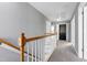 Upstairs hallway featuring neutral carpeting, grey walls, and stairs with white risers and wood railing at 109 Stoneline Ct, Holly Springs, NC 27540