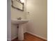 Powder room with pedestal sink, decorative mirror, and hardwood floors at 121 Lumina Pl, Holly Springs, NC 27540
