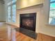A cozy fireplace with tile surround and hardwood floors, near a set of French doors and windows at 121 Lumina Pl, Holly Springs, NC 27540