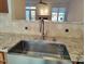 Stainless steel farm sink with granite countertops and tile backsplash open to other spaces at 121 Lumina Pl, Holly Springs, NC 27540