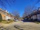 Street view showing the townhome community with neatly lined brick facades and mature bare trees under a bright blue sky at 121 Lumina Pl, Holly Springs, NC 27540