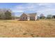 Back exterior of a one-story home on large, partially grass lot with blue skies at 1820 Johnson Rd, Burlington, NC 27217