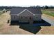 Tan home with a small porch, red front door, black roof, and gravel driveway sits on a large lot at 1820 Johnson Rd, Burlington, NC 27217