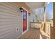 View of the home's covered front porch, featuring a red front door and wooden railings at 1820 Johnson Rd, Burlington, NC 27217