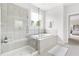 Luxurious bathroom with a large tub, glass shower, neutral tile, and great natural light from the window at 296 Two Creeks Lp, Chapel Hill, NC 27517