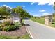 Stone entrance to the Legacy community with manicured landscaping and a winding road under a bright blue sky at 296 Two Creeks Lp, Chapel Hill, NC 27517