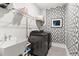 Laundry room with a utility sink, washing machine and dryer, wire shelves, and patterned wallpaper at 296 Two Creeks Lp, Chapel Hill, NC 27517