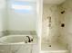 Bright new bathroom showcasing shower, separate bathtub, and neutral tile throughout at 4327 Emeline Way # 10, Fuquay Varina, NC 27526