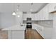 Bright kitchen features white cabinets, stainless steel appliances, kitchen island with sink, and wood floors at 545 Eversden Dr, Zebulon, NC 27597