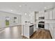 Well-lit kitchen open to the living area, featuring a center island, stainless steel appliances, and hardwood flooring at 556 Eversden Dr, Zebulon, NC 27597