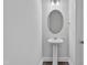 Simple powder room featuring a pedestal sink, round mirror, and fresh white walls, located off the main living space at 556 Eversden Dr, Zebulon, NC 27597