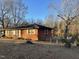 Side view of brick ranch house with mature trees and chain link fence at 6416 Diamond Dr, Raleigh, NC 27610