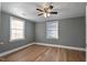 A gray bedroom featuring sleek vinyl floors, a ceiling fan, and ample natural light from two large windows at 408 W Main St, Pine Level, NC 27568