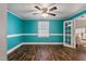 Bright living room painted in turquoise featuring laminate flooring, a large window, and an open doorway at 408 W Main St, Pine Level, NC 27568
