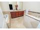 Bathroom featuring a vanity, soaking tub, tiled walls and flooring, and vanity lighting at 9412 Harvest Acres Ct, Raleigh, NC 27617