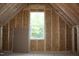 Unfinished attic space featuring wood framing and a window with view of greenery at 1021 Smoke Willow Way # 130, Rolesville, NC 27571