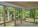 A screened porch has wooden floors, railings, and support posts with a scenic view of the surrounding forest at 1021 Smoke Willow Way # 130, Rolesville, NC 27571