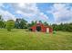 Spacious red barn on large green grassy lot with partially open door at 1610 Woodards Dairy Rd, Middlesex, NC 27557