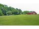 Picturesque red barn on expansive green lawn, surrounded by lush trees at 1610 Woodards Dairy Rd, Middlesex, NC 27557