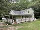 Charming two-story home featuring a metal roof and a welcoming wrap-around porch with white railings at 1610 Woodards Dairy Rd, Middlesex, NC 27557