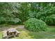 Secluded picnic area with wooden table and chairs amid mature trees and lush greenery at 1610 Woodards Dairy Rd, Middlesex, NC 27557