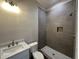 Modern bathroom featuring gray tile, a walk-in shower, and a sleek vanity with granite countertop at 190 Broadleaf Ln, Louisburg, NC 27549