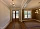 Bright foyer featuring wood-look floors, a modern light fixture, and glass-paned double doors at 190 Broadleaf Ln, Louisburg, NC 27549