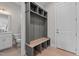 Mudroom with custom gray storage, wood bench, tile flooring, and access to the powder room and doorway at 190 Broadleaf Ln, Youngsville, NC 27596