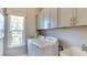 Bright laundry room with modern washer and dryer and storage cabinets at 2948 Hanging Valley Way, Wake Forest, NC 27587