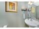 Stylish powder room featuring a pedestal sink, decorative artwork, and modern fixtures at 575 Crystal Spring Dr, Sanford, NC 27332