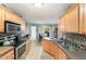 Well-lit kitchen featuring stainless steel appliances, tile backsplash, and a view into dining area at 575 Crystal Spring Dr, Sanford, NC 27332