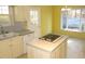 Kitchen with island, white cabinets, and view to backyard at 706 N Crescent Dr, Creedmoor, NC 27522